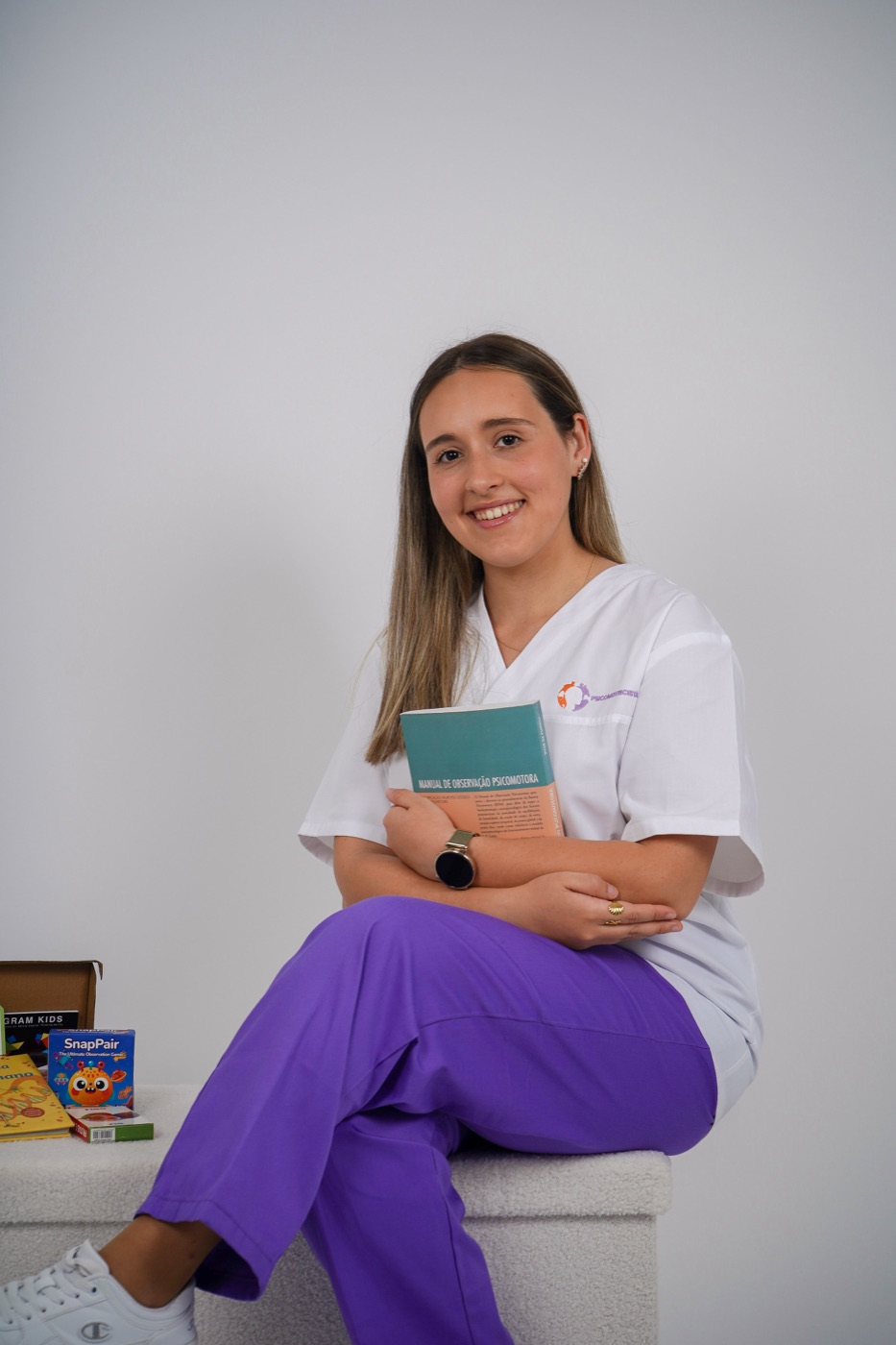 Margarida Pereira sentada, com um livro na mão e caixas de jogos ao lado