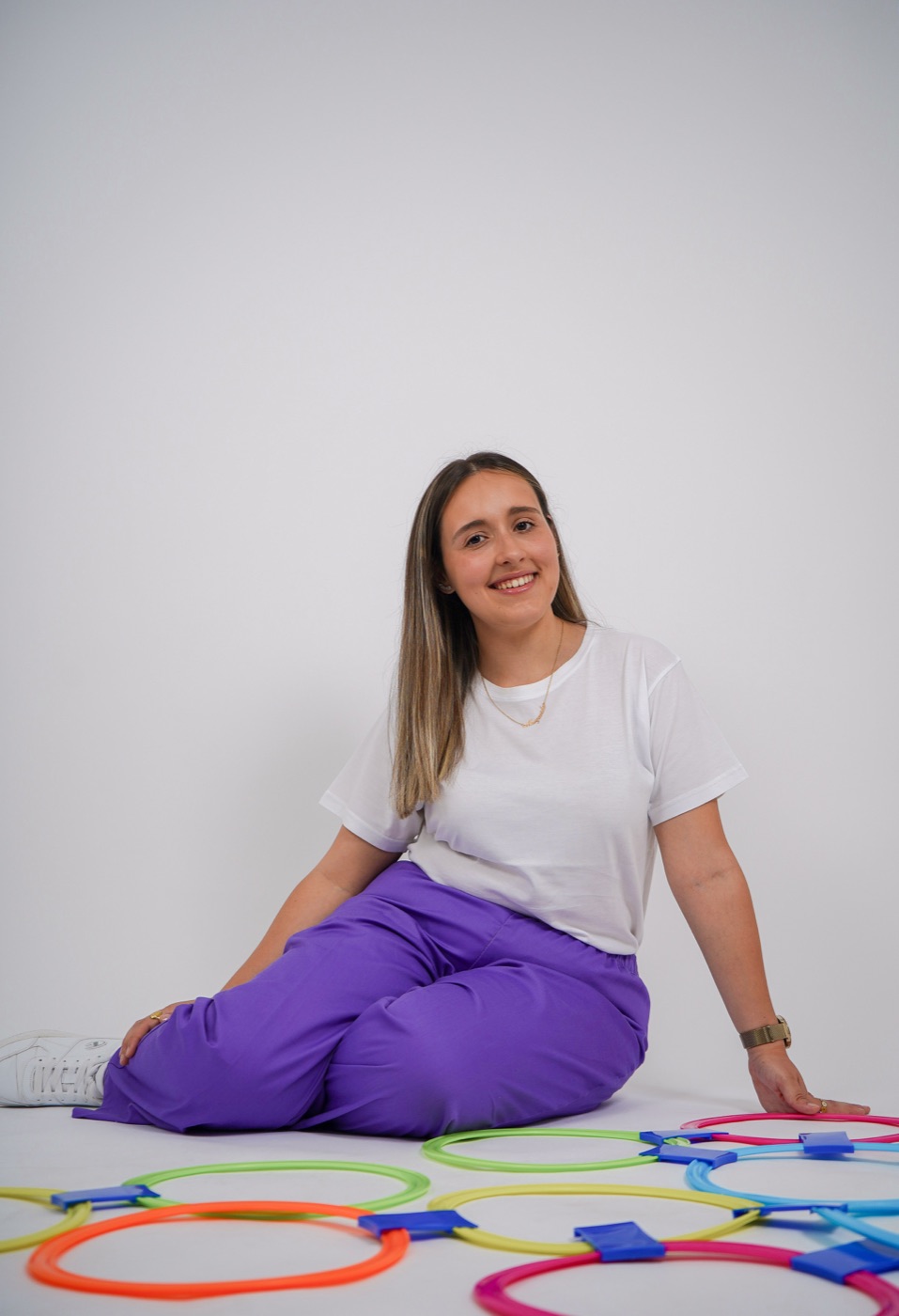 Margarida sentada no chão, rodeada de arcos coloridos